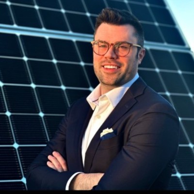 Samuel Hill, Founder and Managing Director of Hilltop Solar Group, in front of a solar array